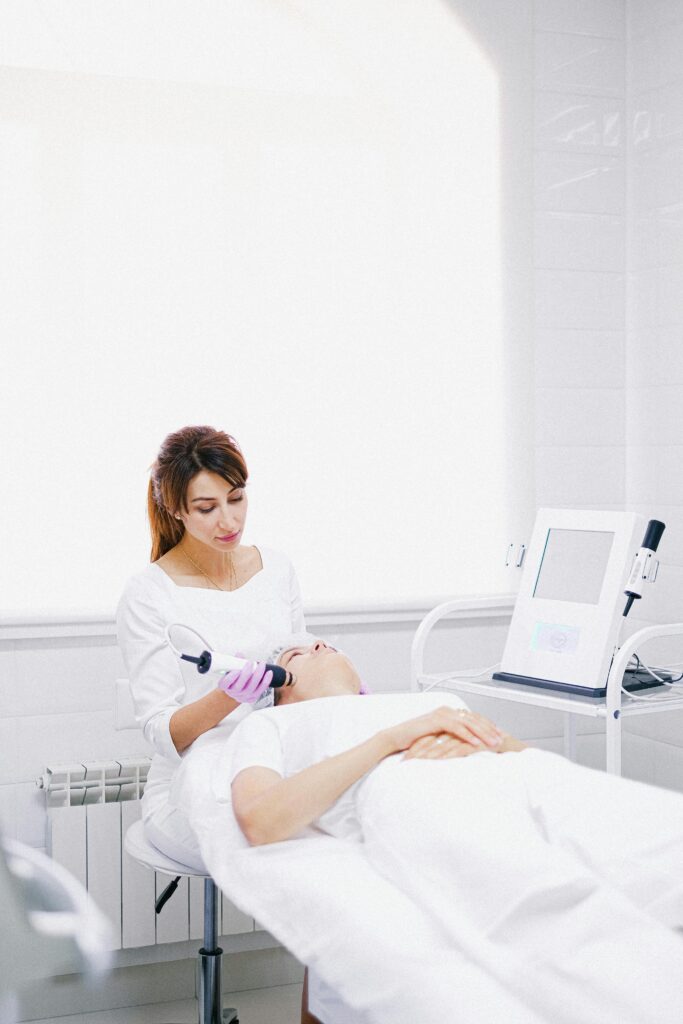 A beautician performs a laser skin care treatment on a patient in a modern clinic.